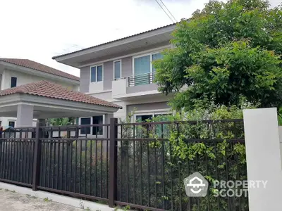 Charming two-story house with lush garden and secure fence in a serene neighborhood.