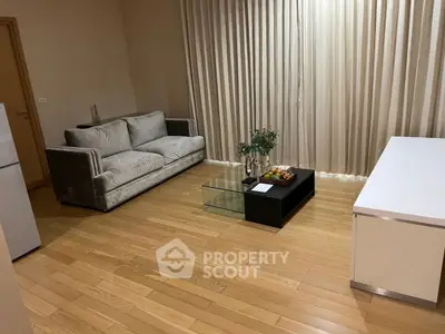 Cozy living room with modern sofa and glass coffee table on wooden flooring.