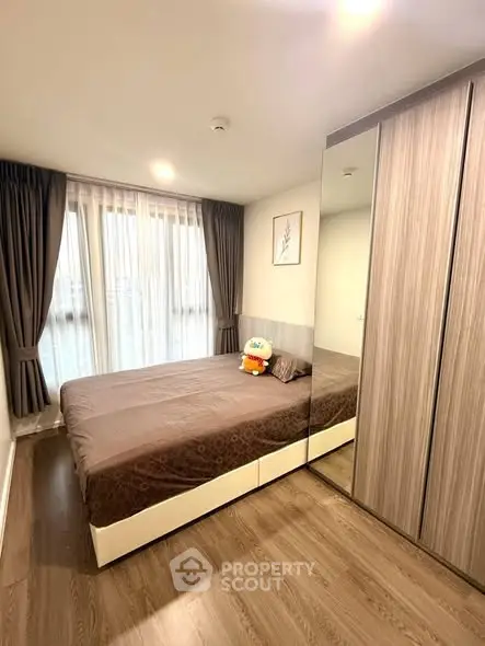 Cozy bedroom with large window and modern wardrobe in stylish apartment