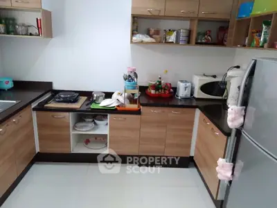 Modern kitchen with wooden cabinets and sleek appliances, featuring a gas stove and microwave.