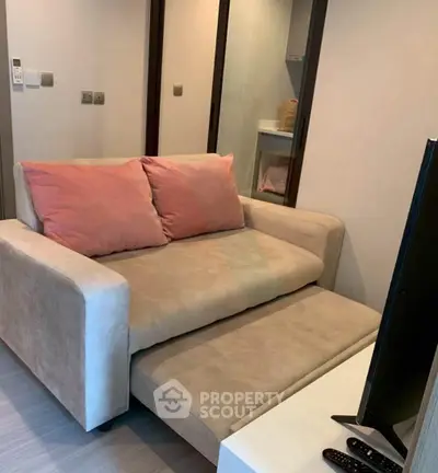 Cozy living room with beige sofa and TV, perfect for relaxation.