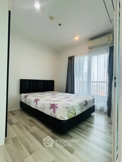 Modern bedroom with large window and stylish decor in a high-rise apartment.