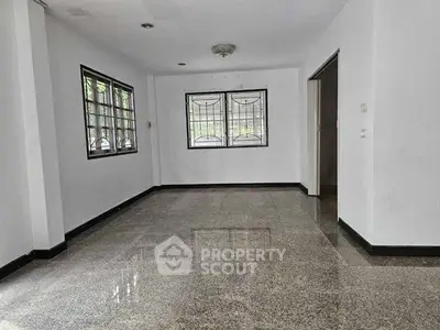 Spacious empty living room with large windows and glossy tiled floor.