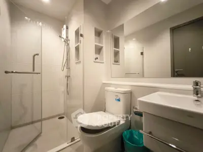 Modern bathroom with glass shower and sleek fixtures in contemporary apartment.