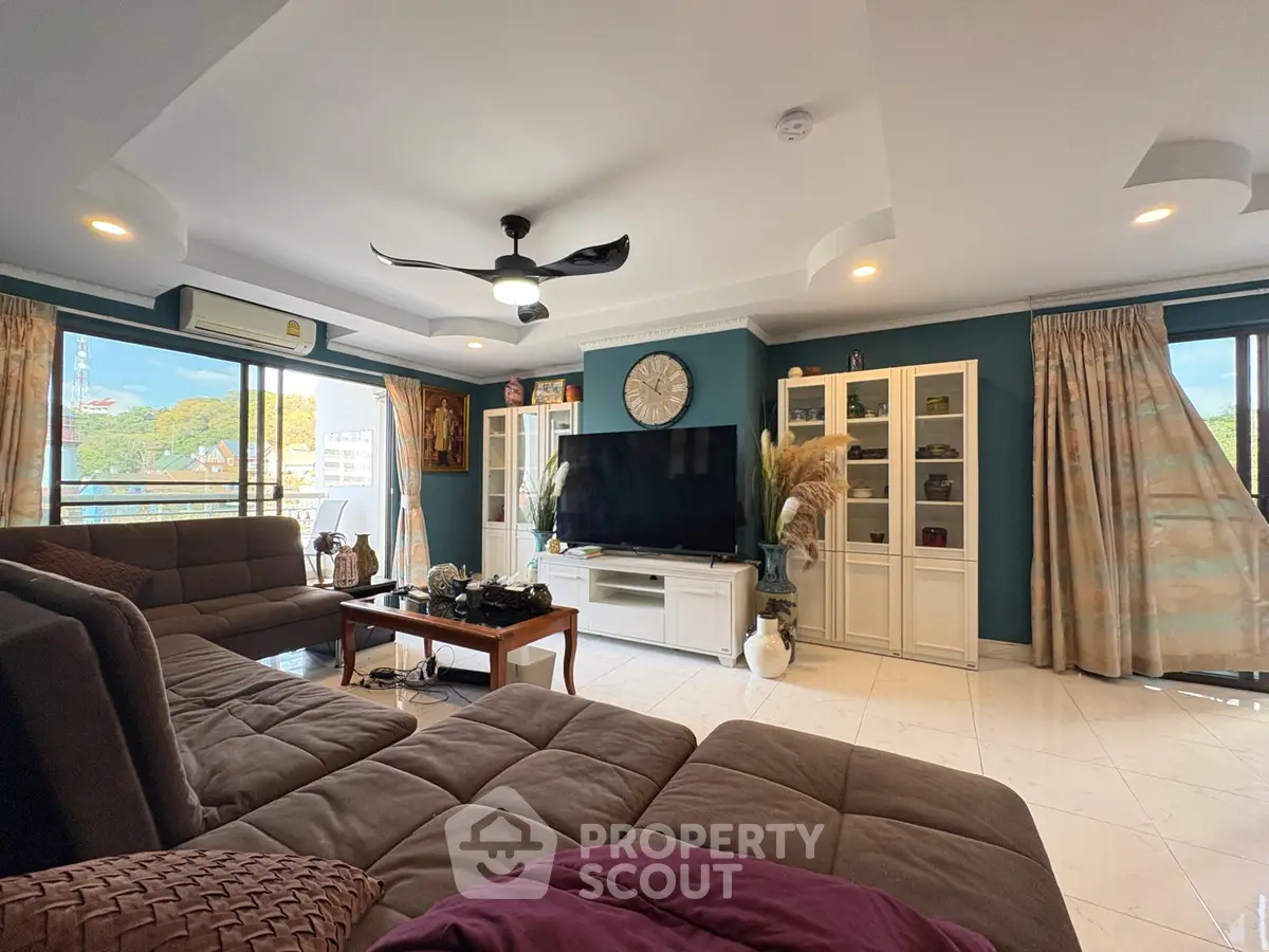 Spacious living room with modern decor and large windows offering natural light and scenic views.