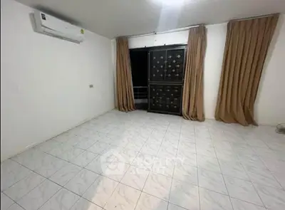 Spacious empty room with tiled floor and large window, perfect for customization.