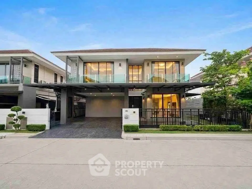 Modern two-story house with large windows and spacious driveway in a suburban neighborhood.
