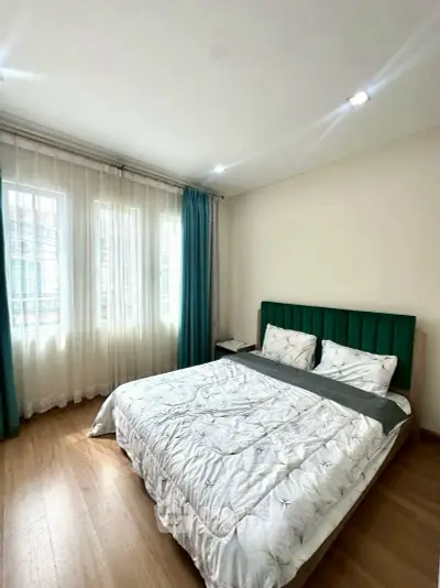 Bright and cozy bedroom with large windows and elegant curtains in modern apartment.