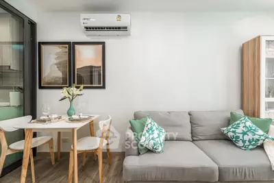 Modern living room with cozy sofa and dining area, featuring stylish decor and air conditioning.