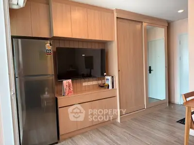 Modern apartment interior with sleek wooden cabinetry and stainless steel fridge