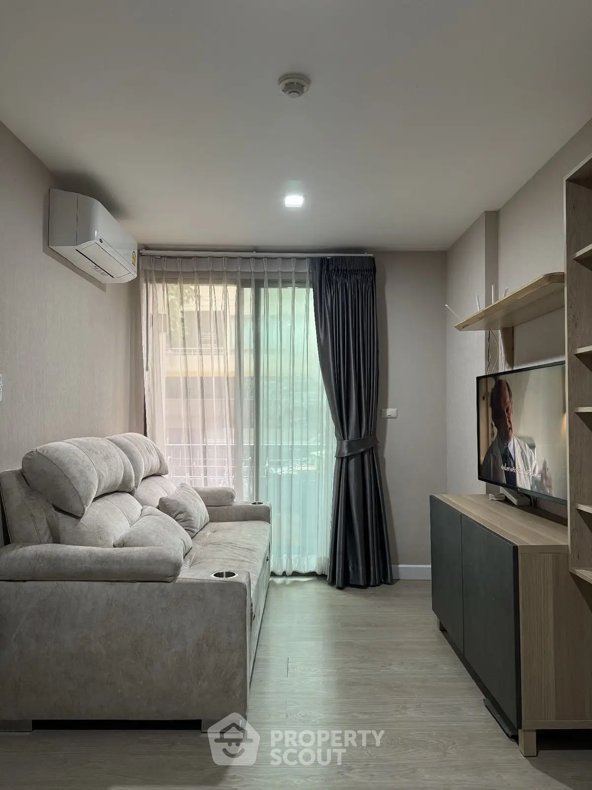 Modern living room with plush sofa, TV, and large window with curtains.