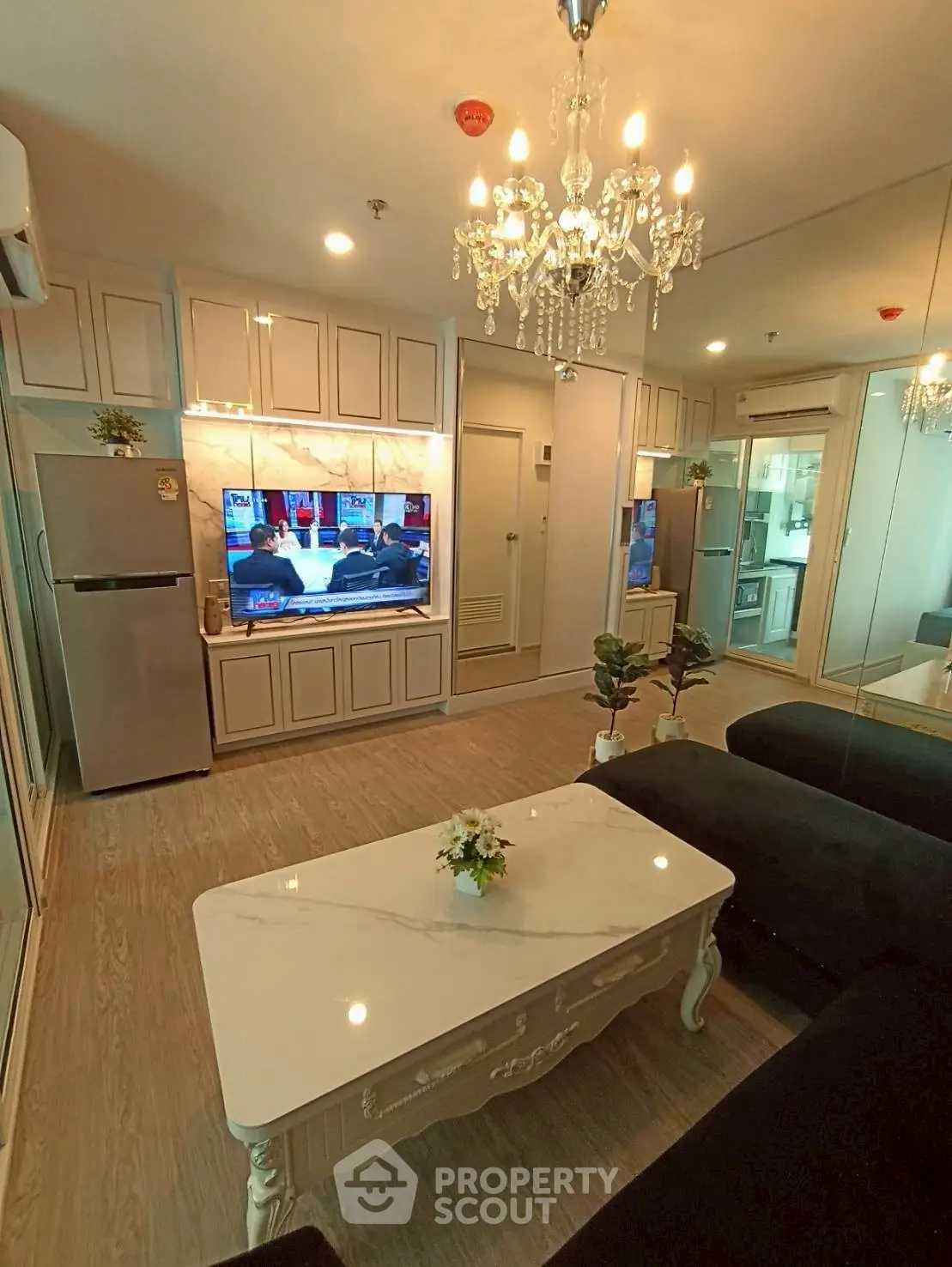 Elegant living room with chandelier, modern TV setup, and stylish furniture in a cozy apartment.