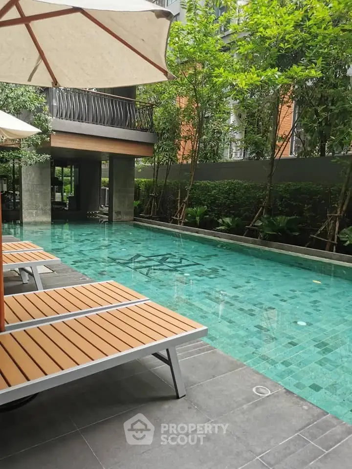 Luxurious outdoor pool area with modern lounge chairs and lush greenery, perfect for relaxation and leisure.