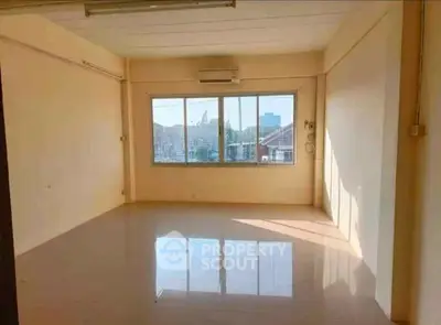 Spacious empty room with large window and city view, perfect for customization.