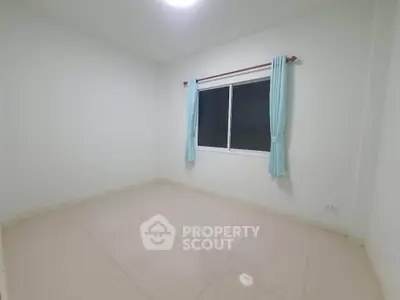 Spacious empty bedroom with tiled floor and large window, perfect for customization.