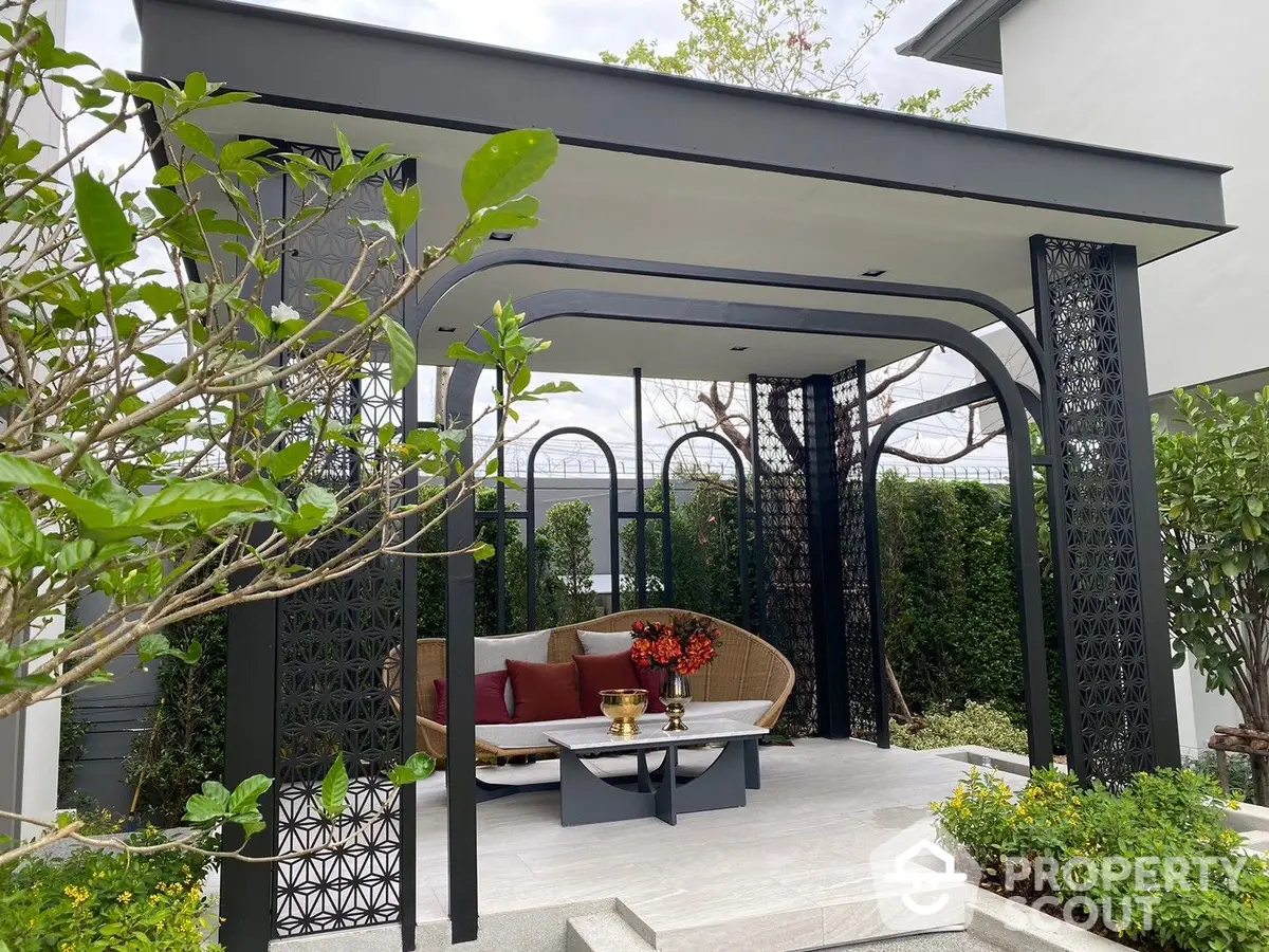 Elegant outdoor lounge area with modern pergola, stylish seating, and lush greenery, perfect for relaxation and entertainment.