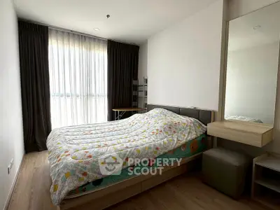Spacious bedroom with large window and modern furnishings in a stylish apartment.
