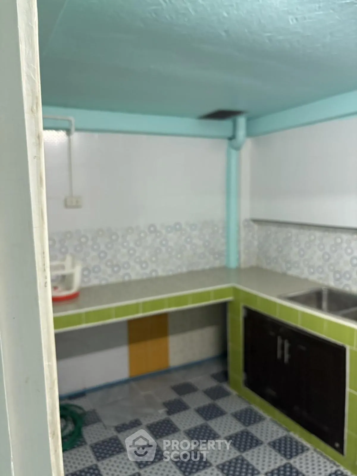 Cozy kitchen with colorful tiled flooring and green accents, featuring a double sink and ample counter space.