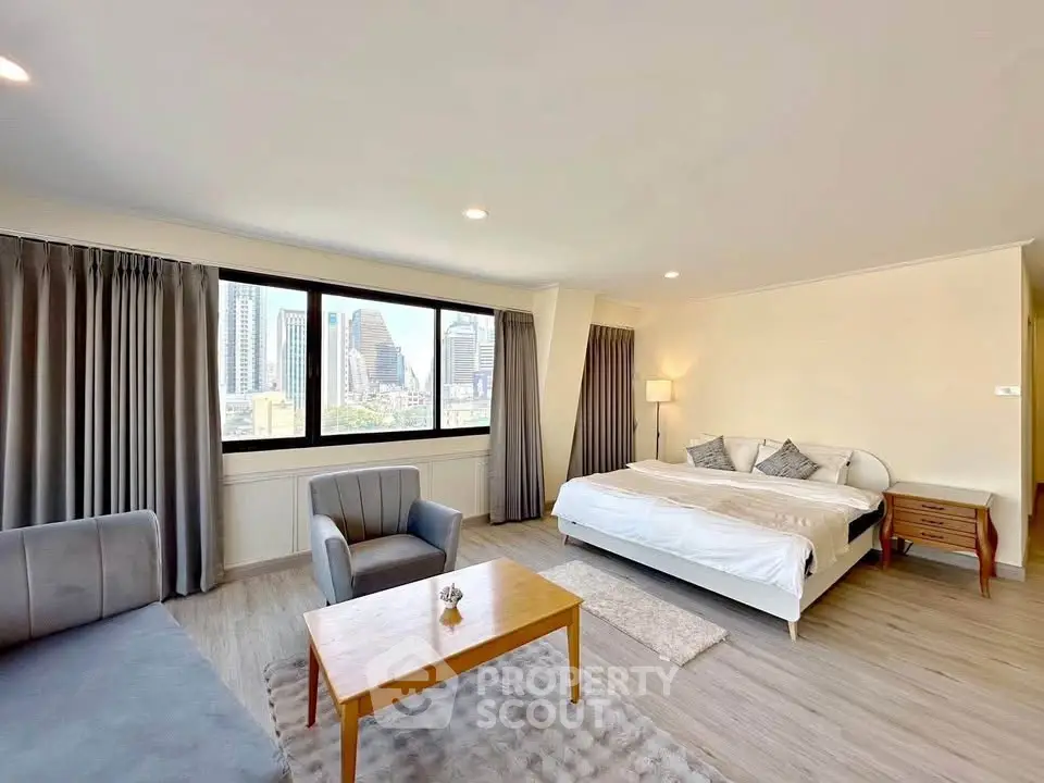 Spacious modern bedroom with city view, featuring elegant furniture and ample natural light.