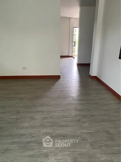 Spacious empty room with wooden flooring and natural light, ideal for customization.
