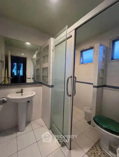 Spacious bathroom with glass shower and modern fixtures in a well-lit apartment.