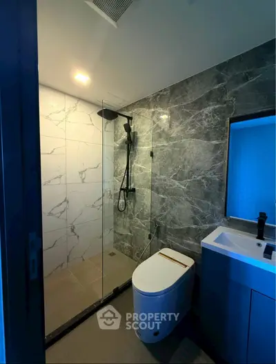 Modern bathroom with sleek marble tiles and glass shower enclosure