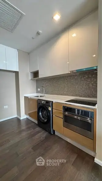 Modern kitchen with sleek cabinetry, integrated appliances, and stylish backsplash in a contemporary apartment.