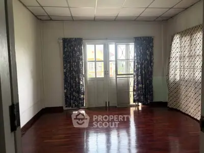 Spacious room with wooden floors and large windows for natural light