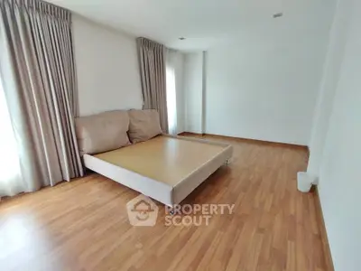 Spacious bedroom with wooden flooring and large windows for natural light