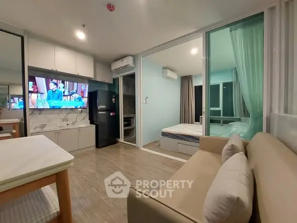 Modern open-plan living room with kitchen and bedroom in compact apartment.