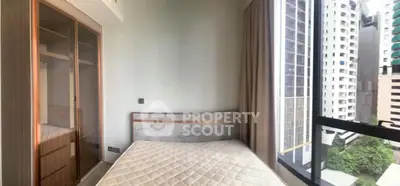 Modern bedroom with large window and built-in wardrobe in high-rise apartment