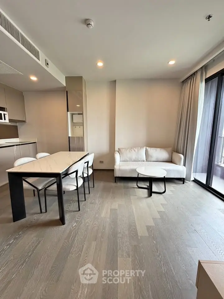 Modern living room with open kitchen and balcony view in a stylish apartment.