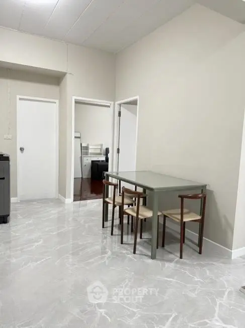 Spacious dining area with modern table and chairs, featuring sleek marble flooring and neutral walls.