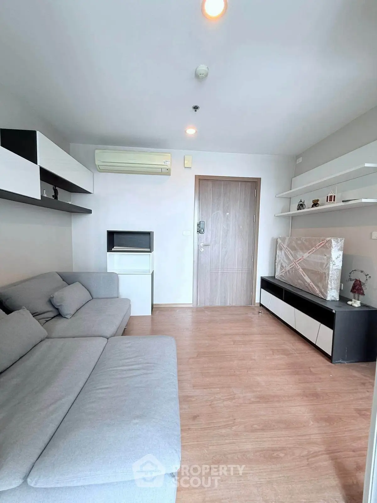 Modern living room with sleek furniture and wooden flooring, featuring a cozy gray sofa and stylish shelving.