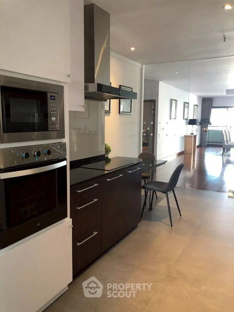 Modern kitchen with sleek appliances and open layout leading to dining area.