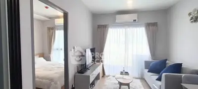 Modern living room with cozy sofa, TV, and natural light next to a bedroom in a stylish apartment.