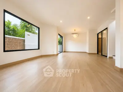Spacious modern living room with large windows and wooden flooring