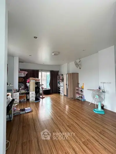Spacious living room with wooden flooring and ample natural light, perfect for cozy family gatherings.