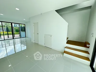 Spacious modern living room with glossy tiled floors and staircase, abundant natural light.