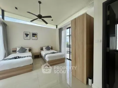 Spacious modern bedroom with twin beds and large windows offering natural light.