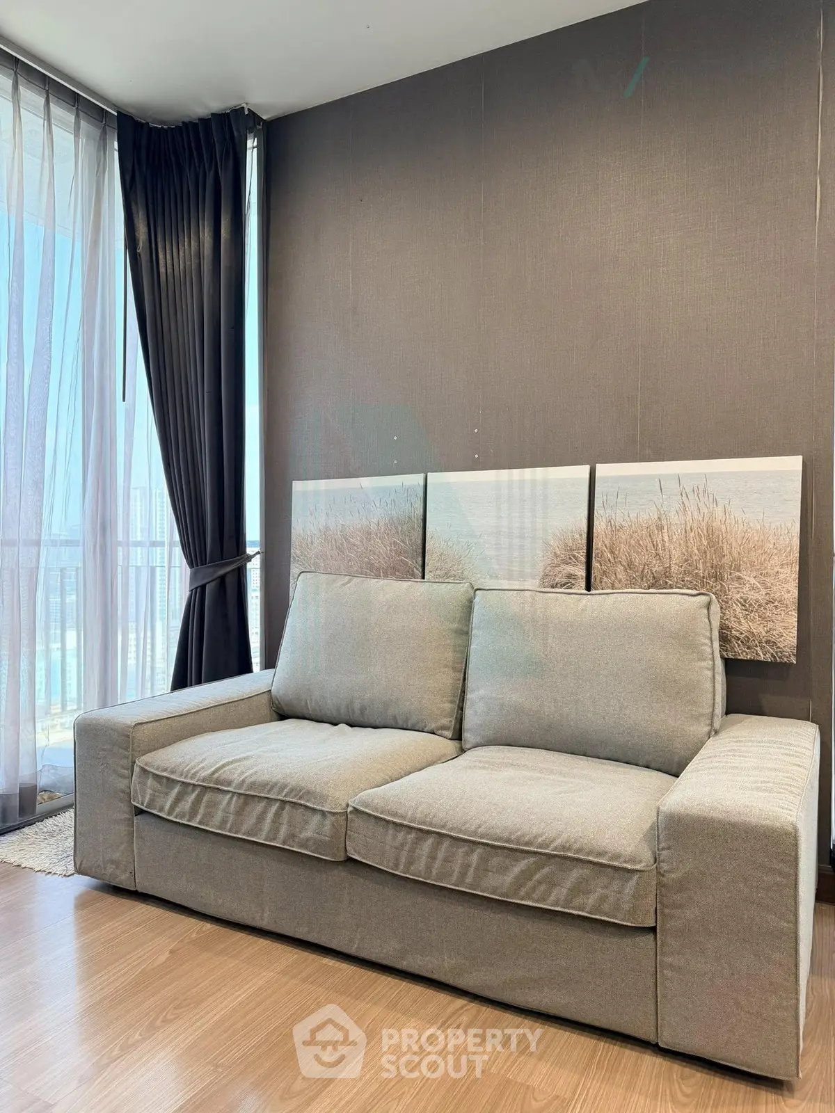 Modern living room with stylish gray sofa and floor-to-ceiling windows offering natural light and scenic views.