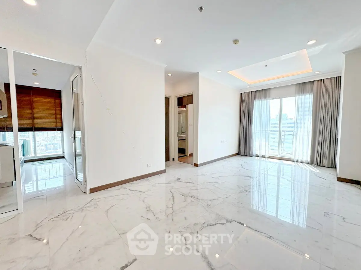 Spacious modern apartment with marble flooring and large windows offering city views.