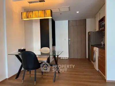 Modern dining area with glass table and stylish lighting in a cozy apartment.