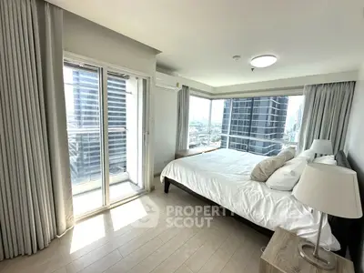 Spacious bedroom with large windows and city view in modern high-rise apartment.