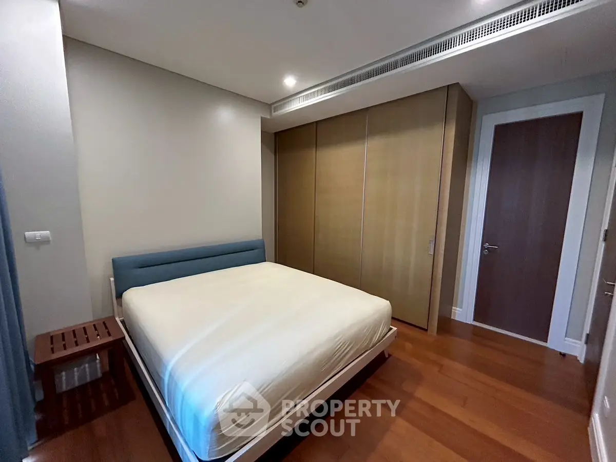Spacious bedroom with modern design and wooden flooring in a luxury apartment.