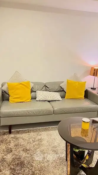 Stylish living room with modern grey sofa and vibrant yellow cushions.