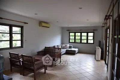 Spacious living room with modern furniture and large windows offering garden views.