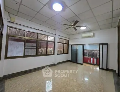 Spacious empty room with ceiling fan and large windows, ideal for customization.