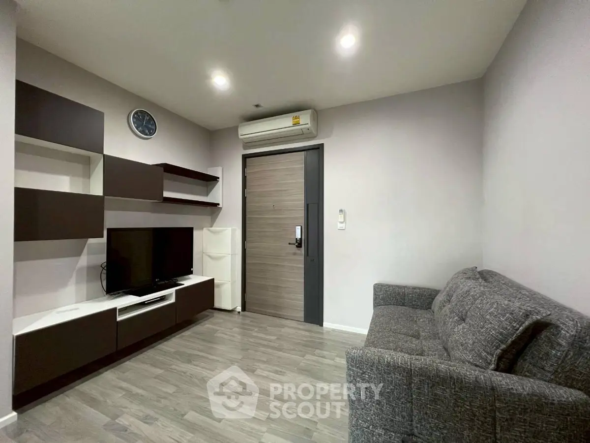 Modern living room with sleek furniture and wall-mounted TV in a cozy apartment.