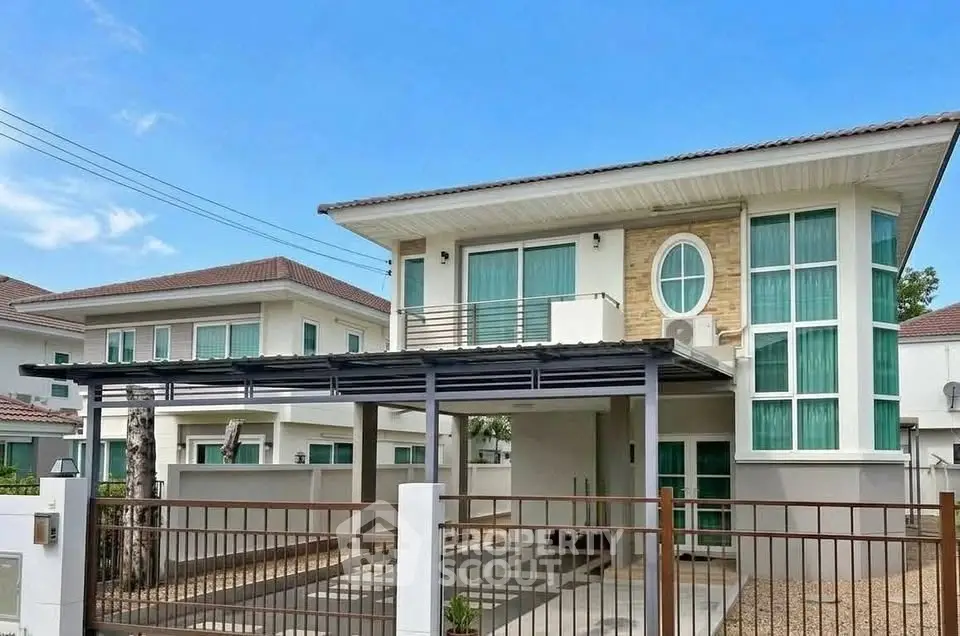 Modern two-story house with large windows and gated driveway